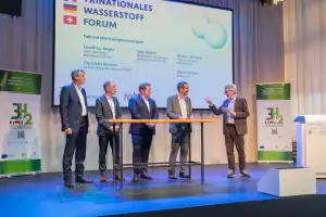 Das Bild zeigt stehende diskutierende Männer auf der Bühne an der Veranstaltung Wasserstoffforum 2025.