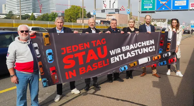 Foto der Petenten auf der Schwarzwaldbrücke (v.l.) Markus Haas, NQV Breite-Lehenmatt;  Daniel Seiler, ACS beider Basel; Lukas Ott, TCS beider Basel; Hans-Peter Ebneter, NQV Oberes  Kleinbasel; Tamara Hunziker, Gewerbeverband Basel-Stadt; Silvan Buchecker, Handelskammer beider  Basel; Birgit Kron, TCS beider Basel.  