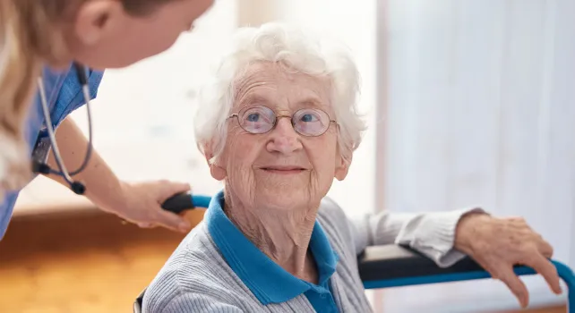 Pflegerin spricht mit Seniorin 
