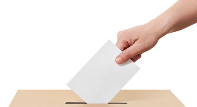 Das Bild zeigt eine Hand, die das Abstimmungscouvert in die Urne wirft