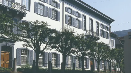 Regierungsgebäude in Liestal weiss mit grauen Fensterläden und fünf Bäumen