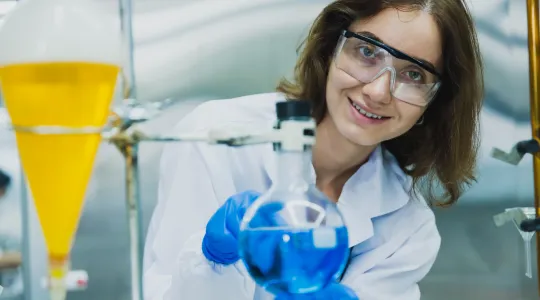 Das Bild zeigt eine junge Frau beim Löten vor technischen Geräten