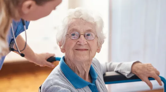 Pflegerin spricht mit Seniorin 