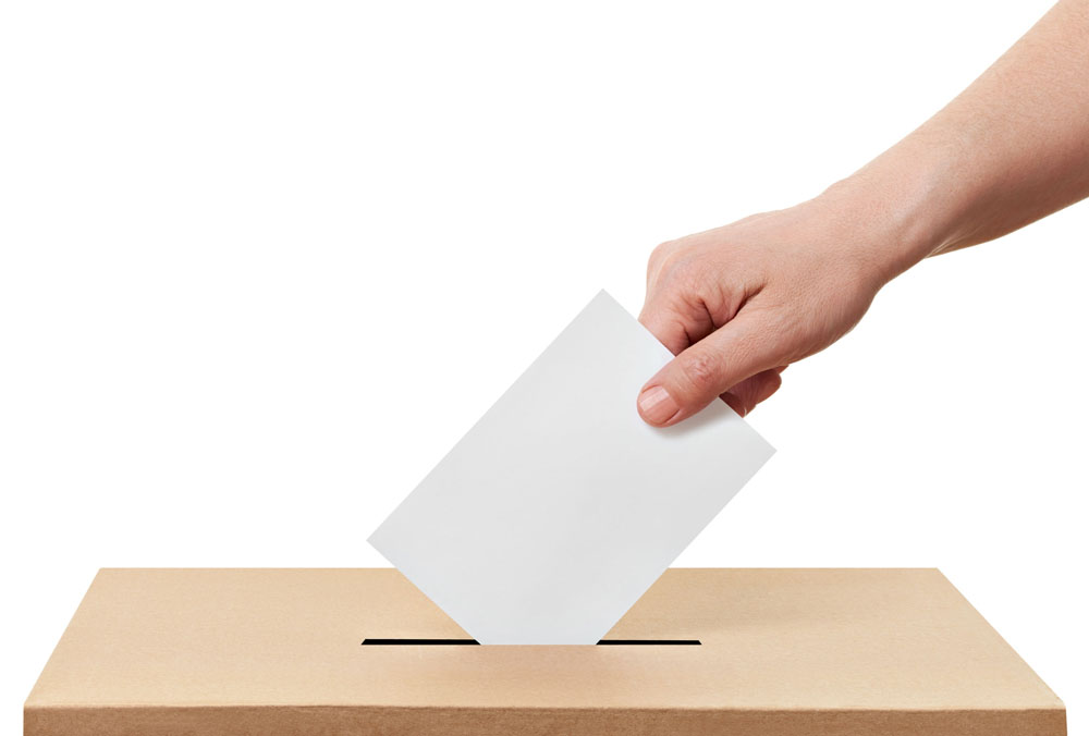 Unsere Abstimmungsempfehlungen Das Bild zeigt eine Hand, die das Abstimmungscouvert in die Urne wirft